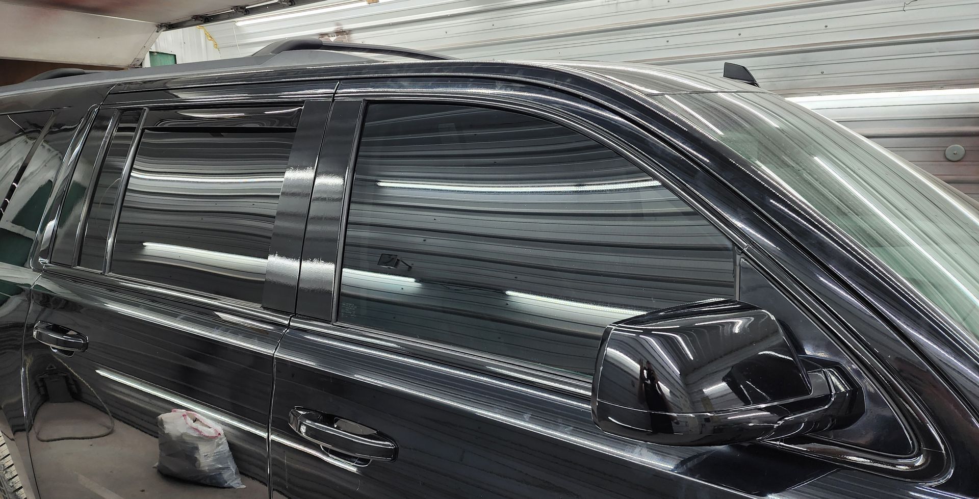 A black car is parked in a garage with the door open