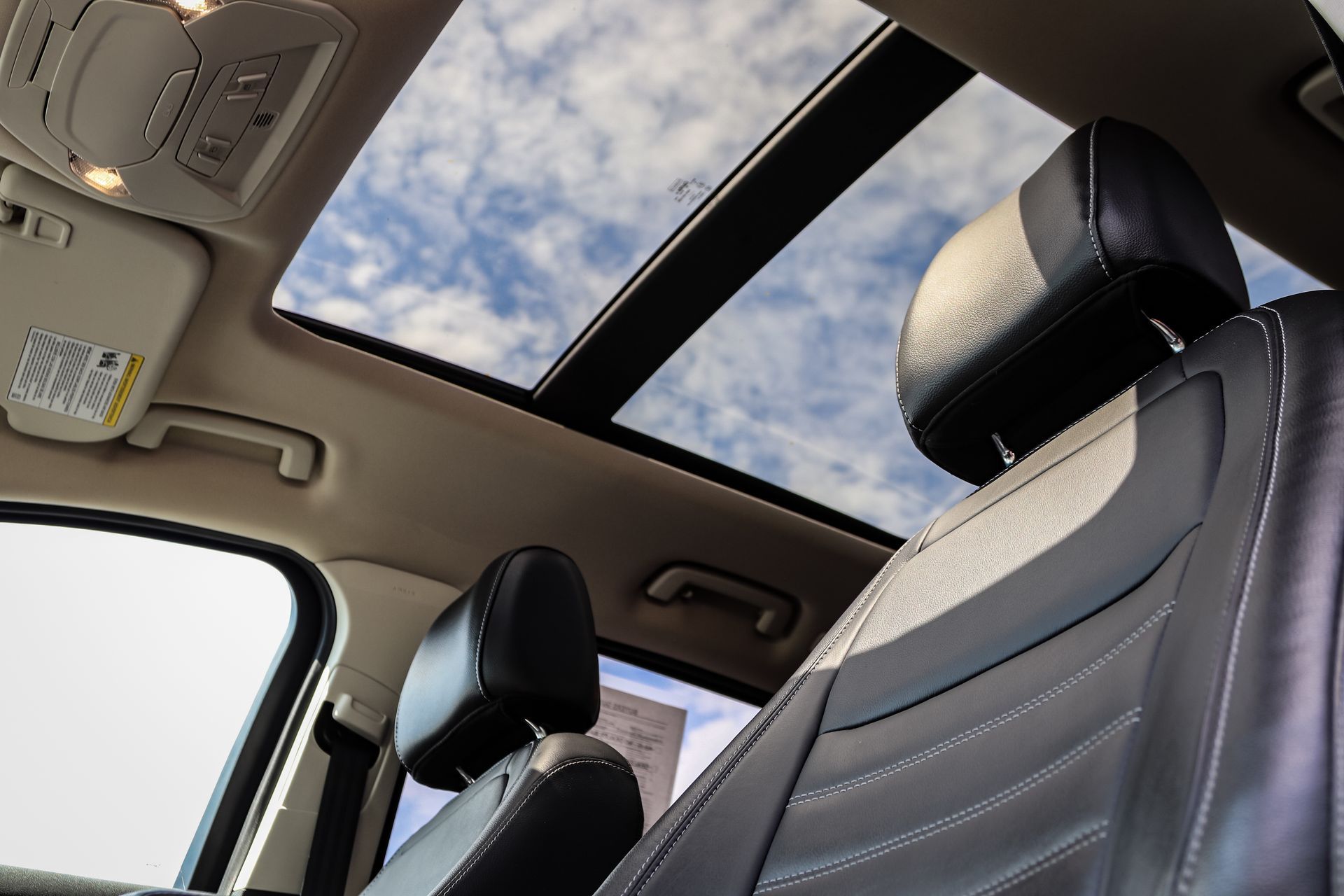 The sunroof of a car is open and looking up at the sky.