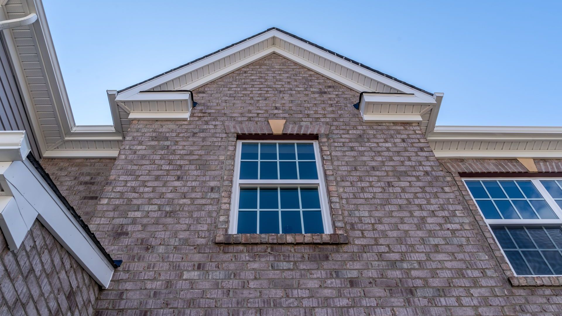 Regardant une maison en brique avec deux fenêtres et un ciel bleu en arrière-plan.