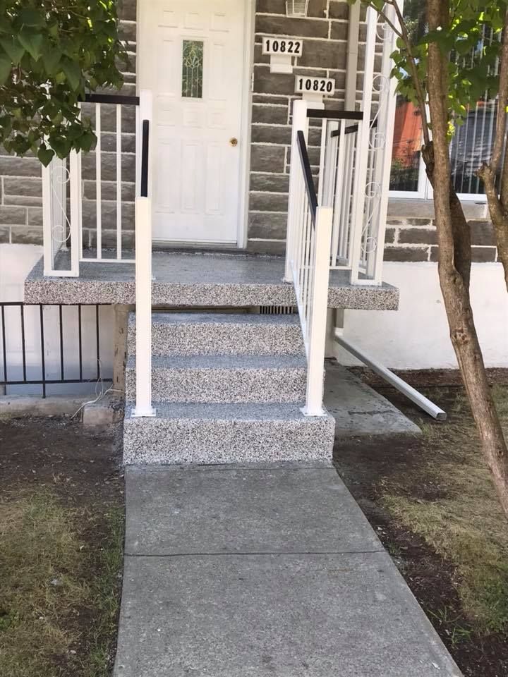 Une passerelle en béton menant à la porte d'entrée d'une maison