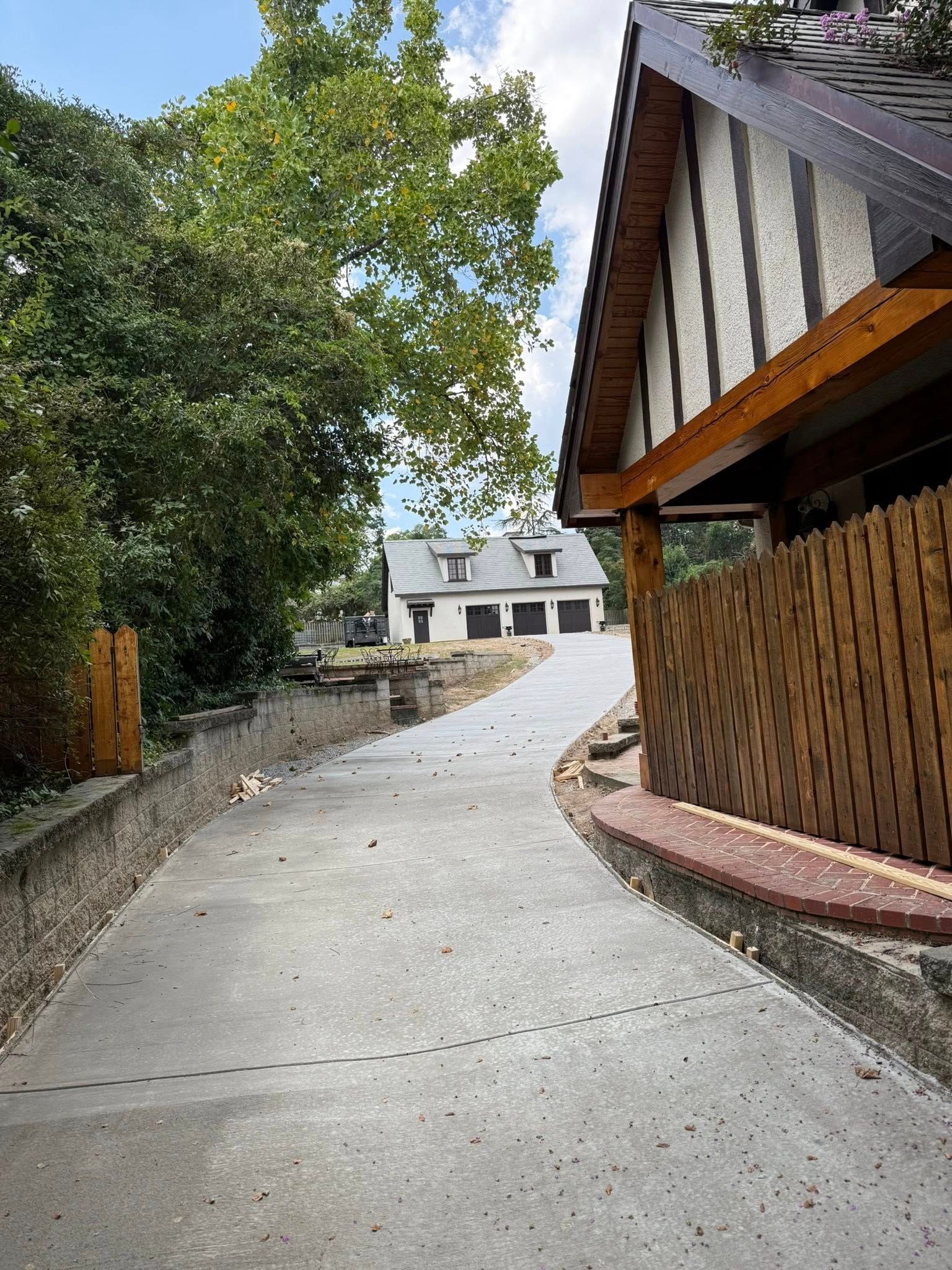 Concrete driveway leading to a building with a multi-bay garage and other buildings.