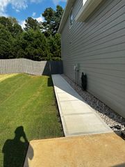 Concrete ramp leading from a house to the yard.  Gray siding, gravel bed, and wooden fence visible.