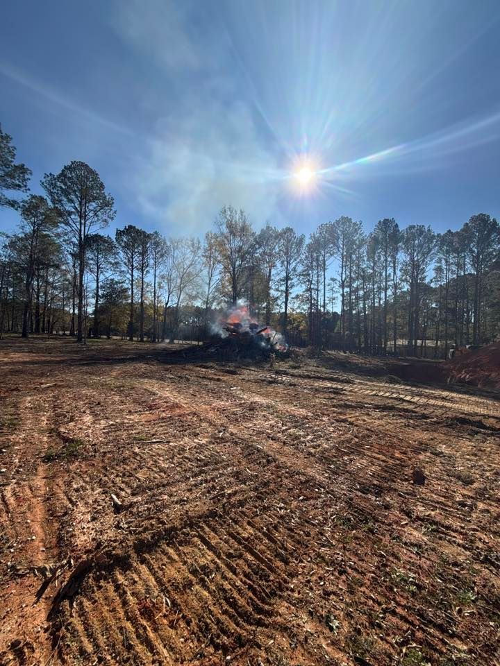 Clearing land with fire: smoke rising from a brush pile under a bright sun.