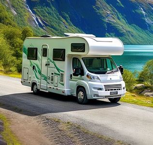 White RV driving on a scenic mountain road beside a turquoise lake