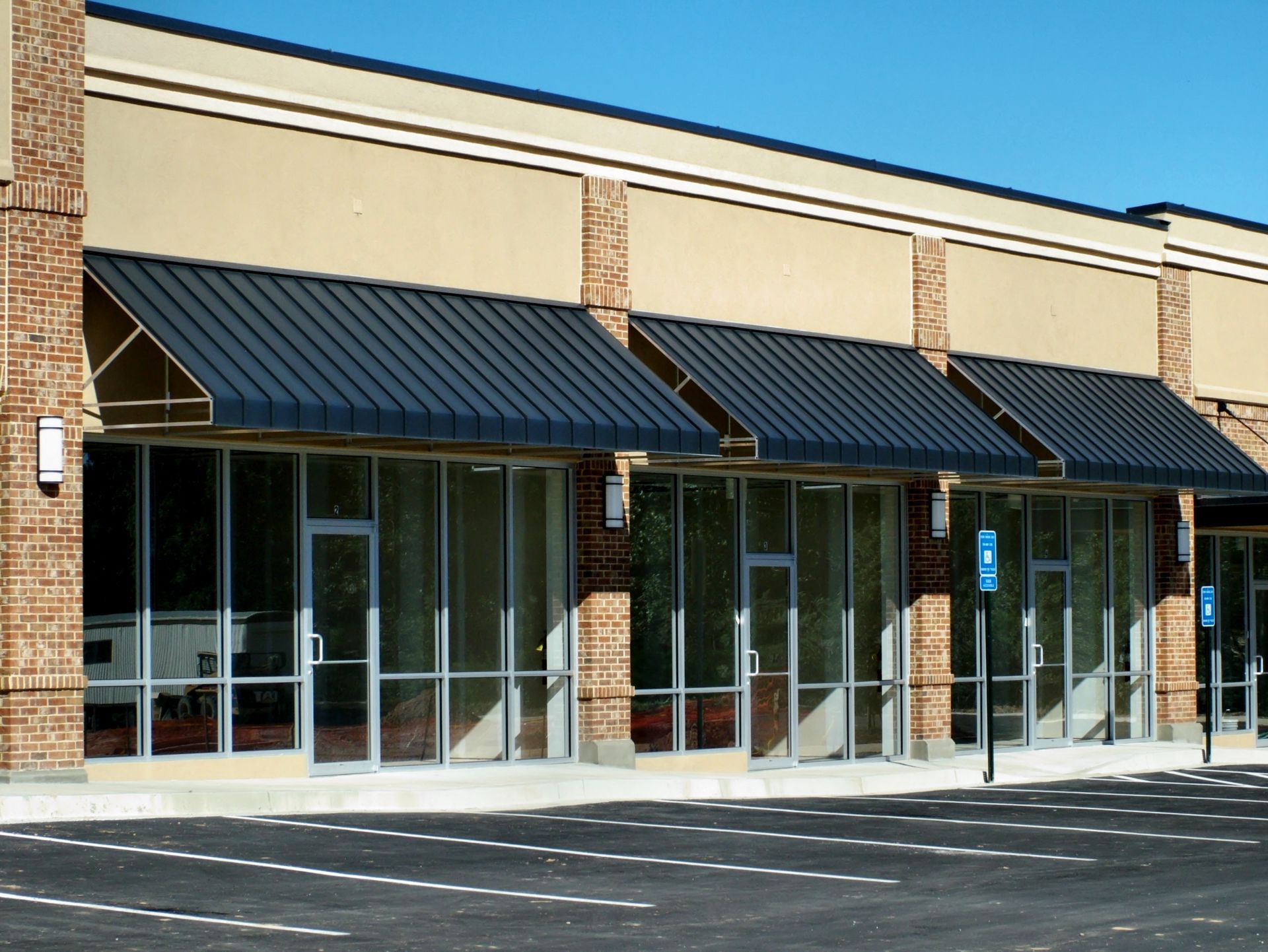 Empty storefronts with black awnings and glass doors in a shopping plaza