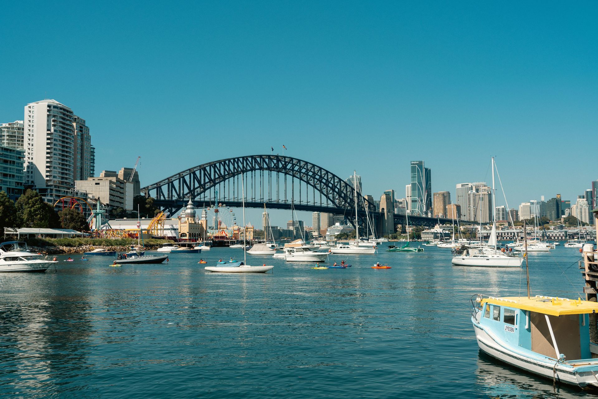 Sydney Harbour with the Harbour Bridge, sailboats, and city skyline on a sunny day