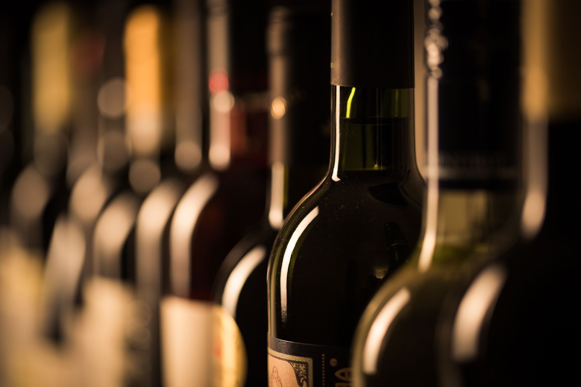 A row of bottles of wine are lined up in a row.