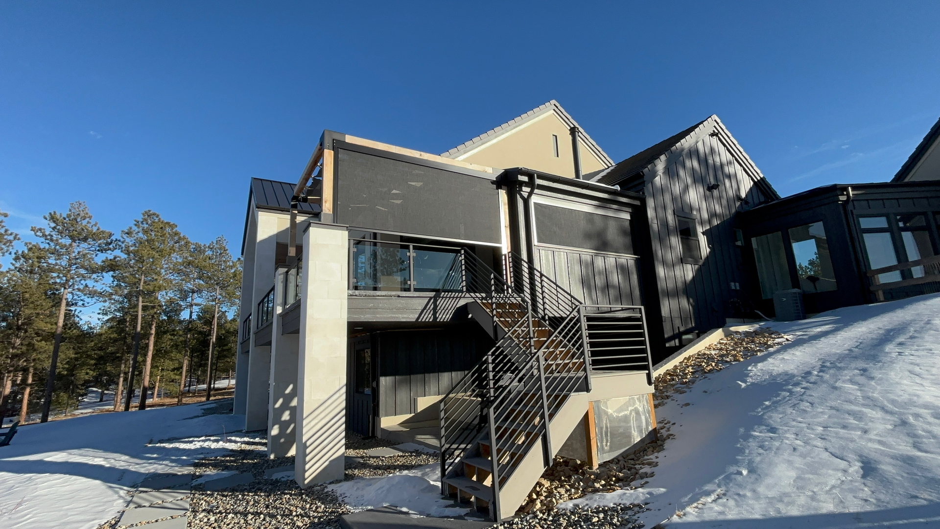 Modern building exterior with snowy ground, metal staircase, and blue sky.