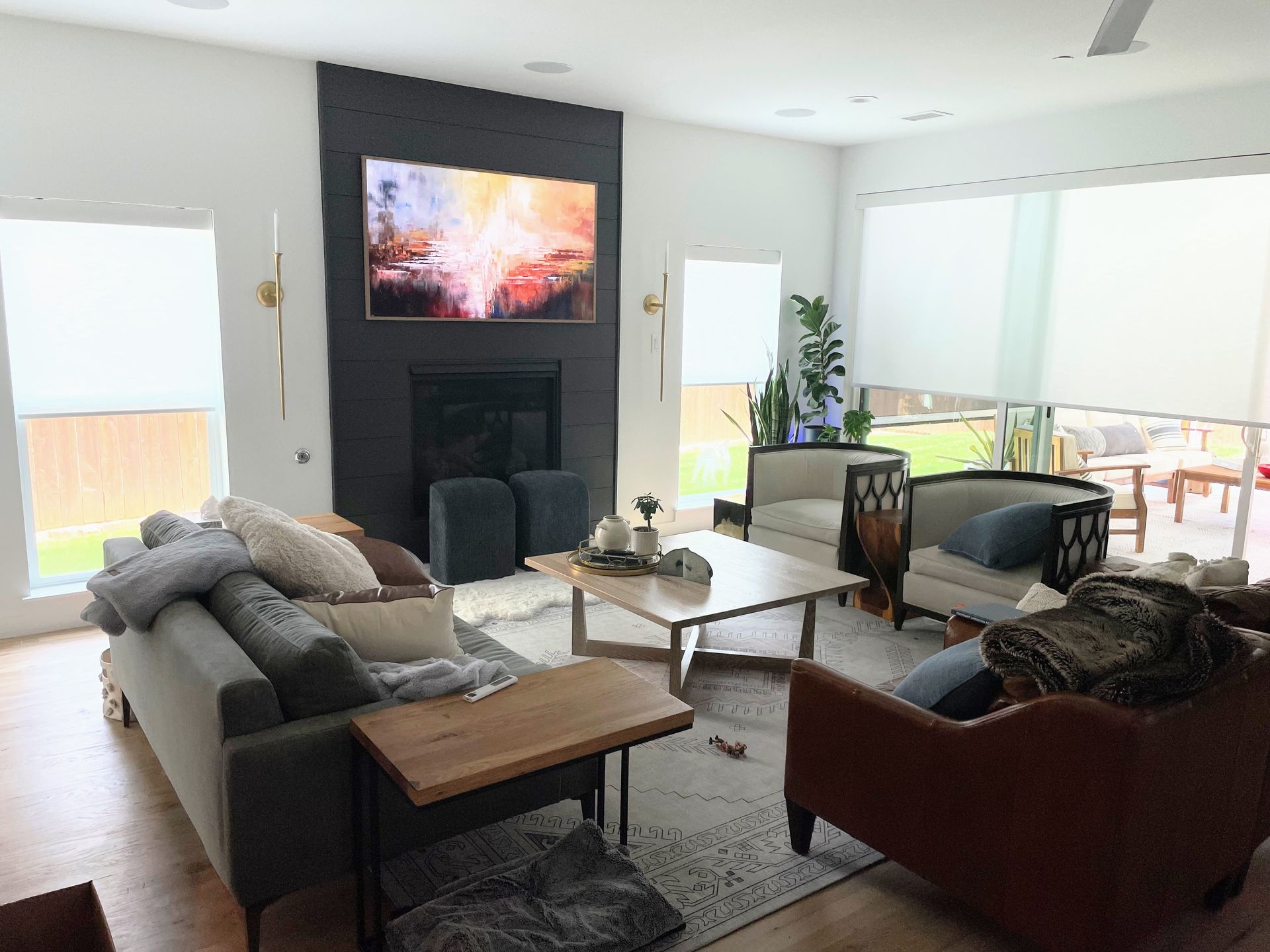 Living room with fireplace, art, large windows, various seating, neutral colors.
