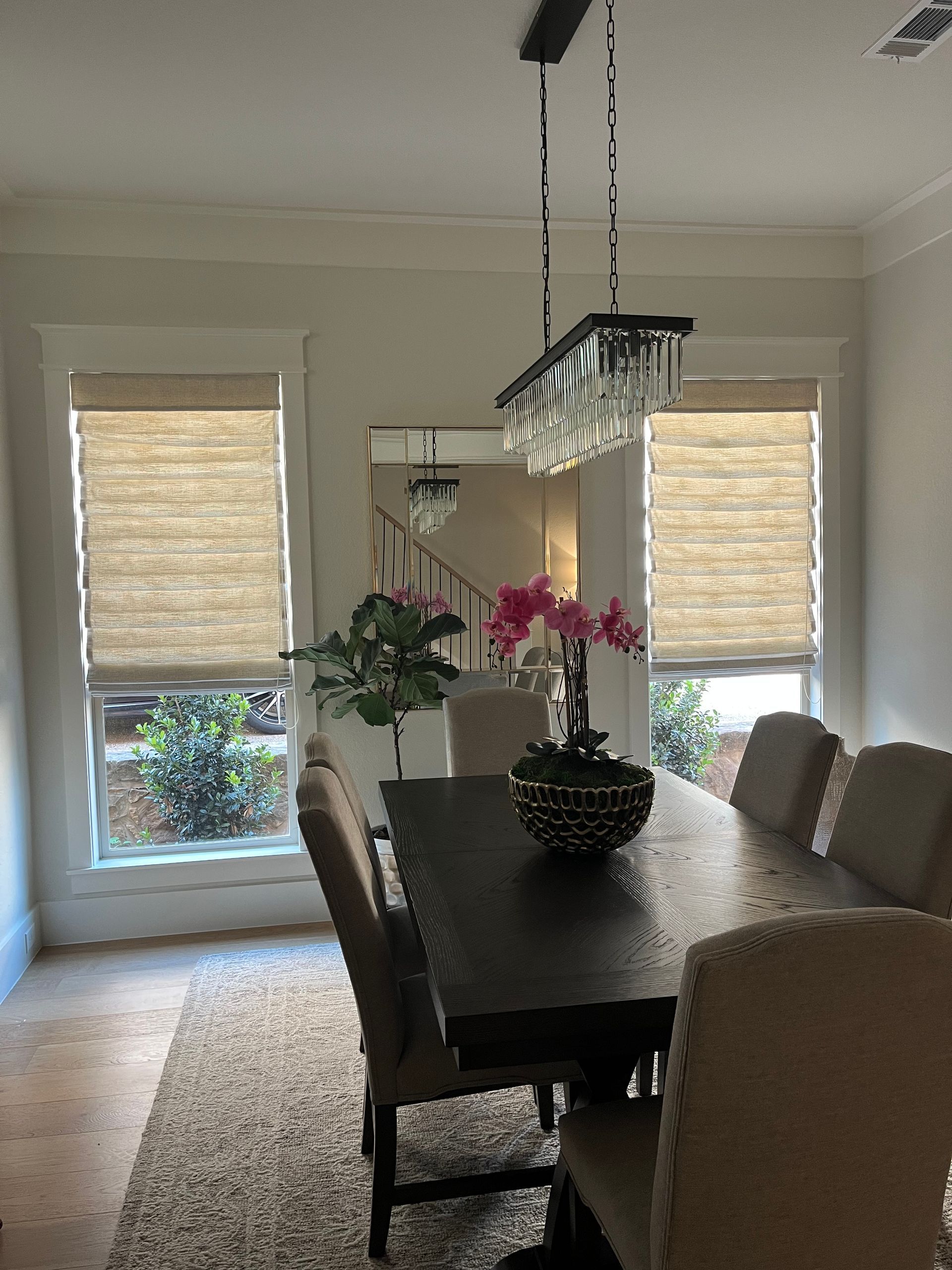 Dining room with a long table, chairs, windows with shades, and a chandelier.