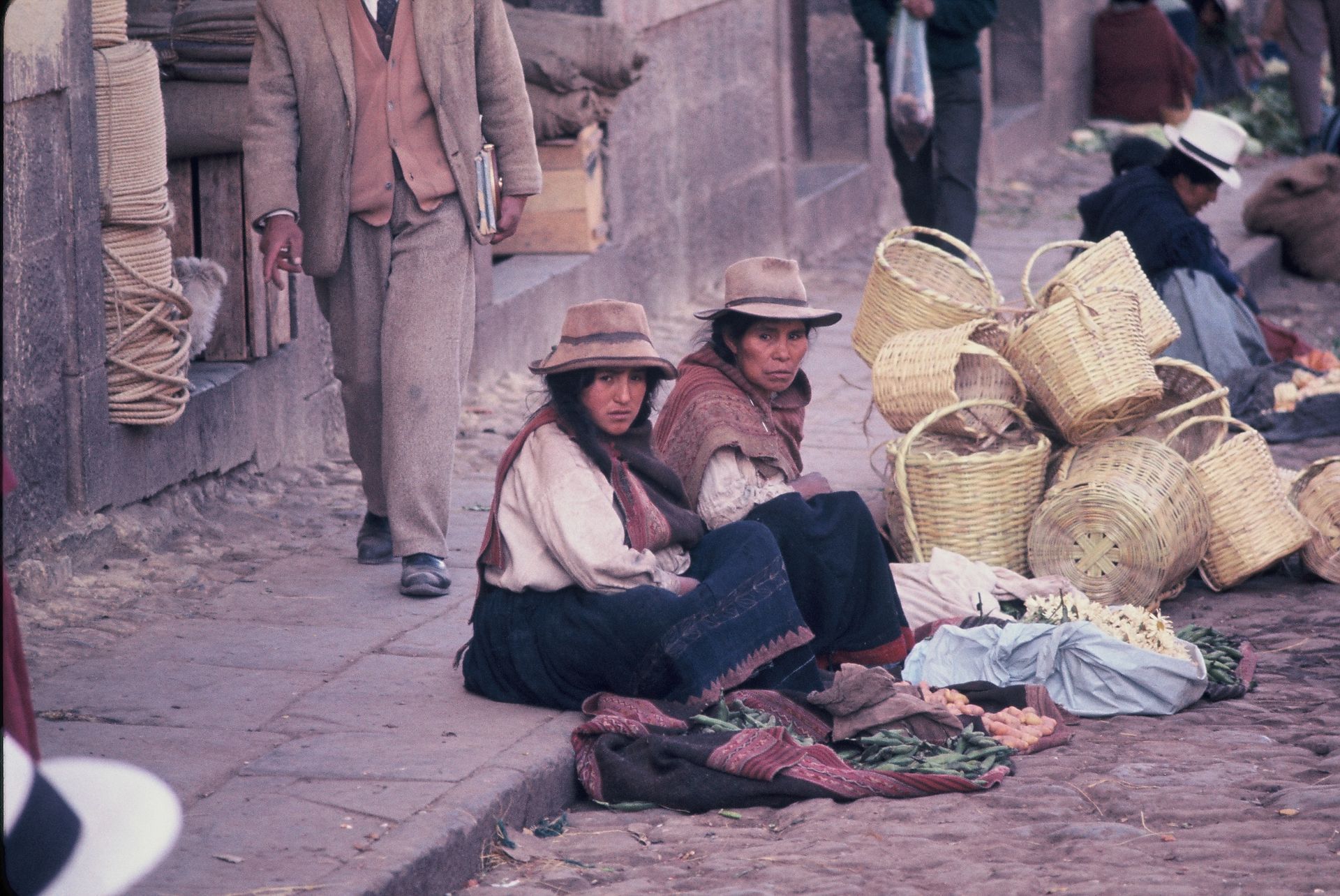 A group of people are sitting on the sidewalk selling baskets
