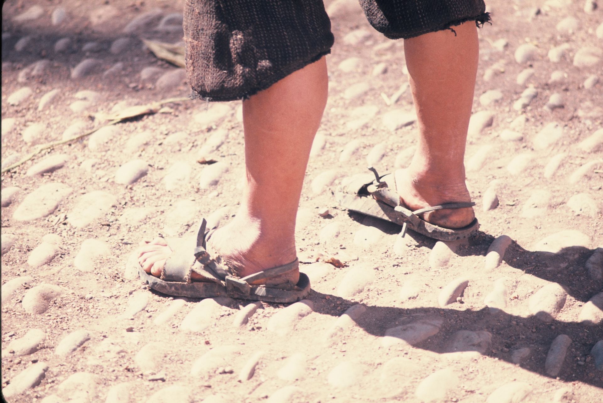 A person standing in the sand wearing flip flops