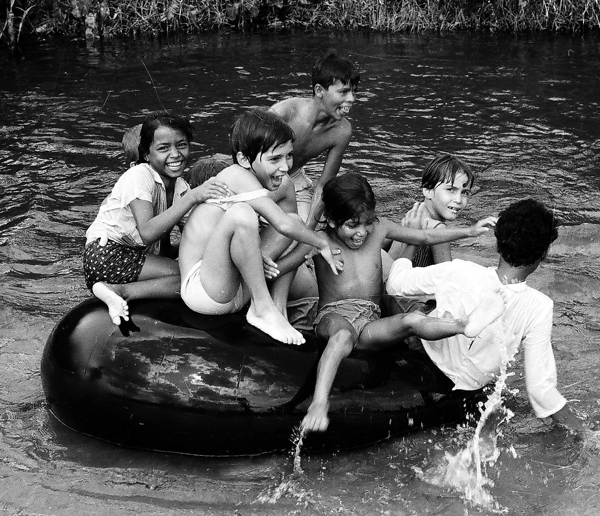 A black and white photo of children playing in a river