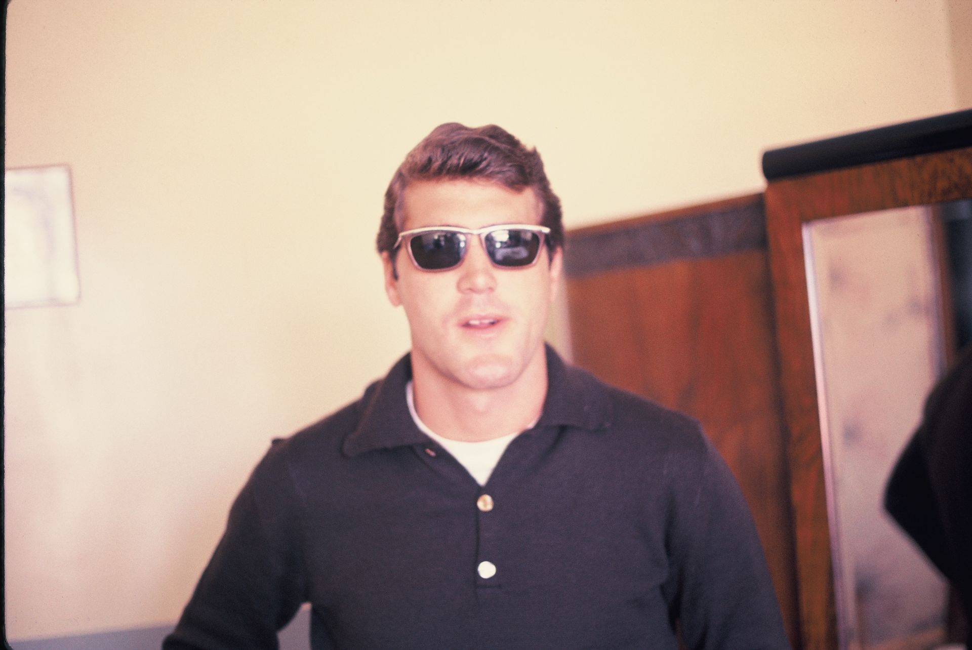 A man wearing sunglasses is standing in a room