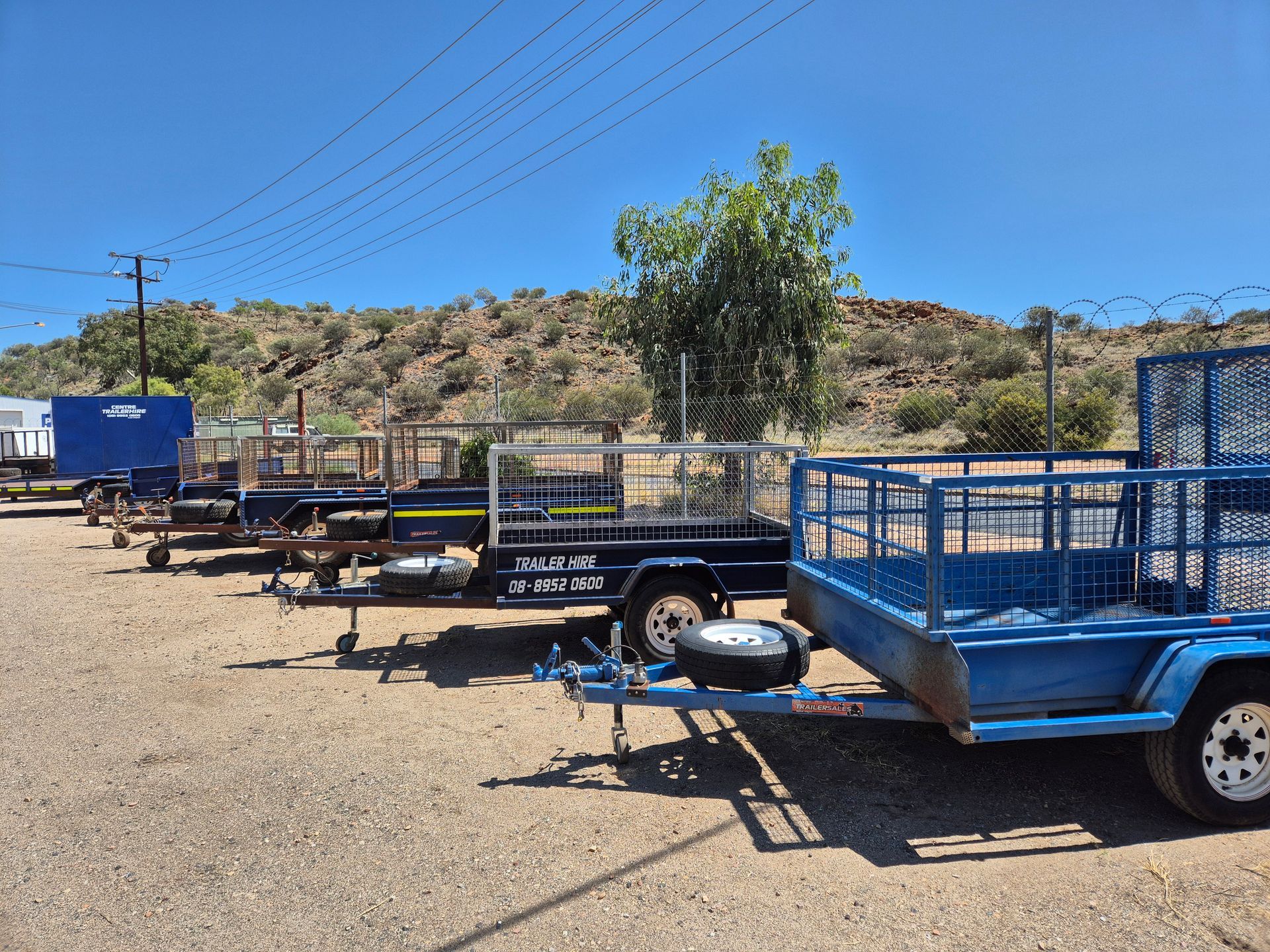 Trailers Parked in A Row on A Gravel Lot Under a Bright Blue Sky — Centre Trailer Sales In Alice Springs, NT