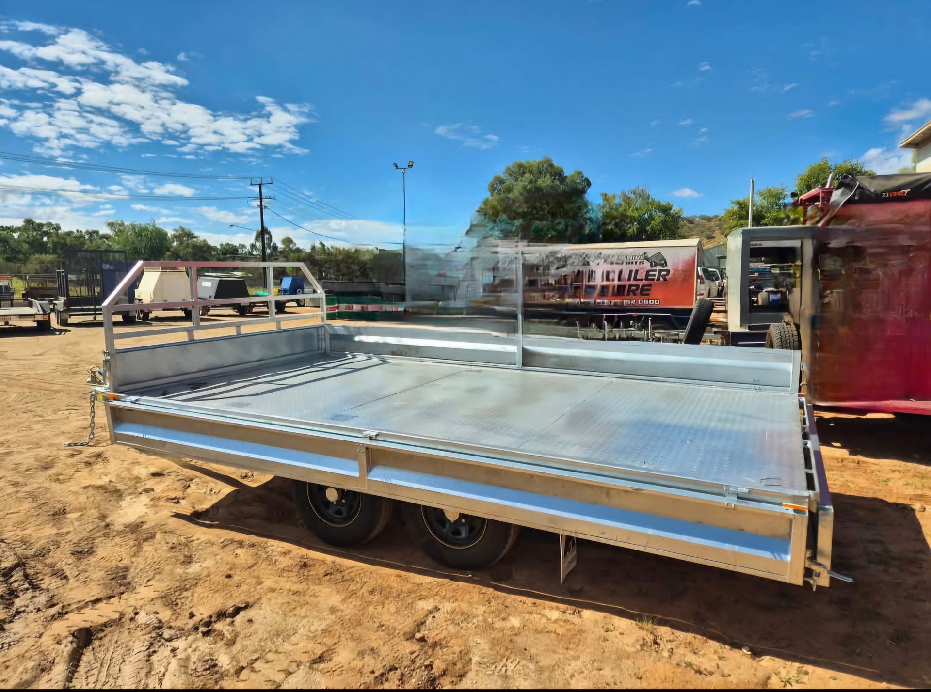 Flatbed Trailer Parked on Dirt Under a Blue Sky — Centre Trailer Sales In Alice Springs, NT