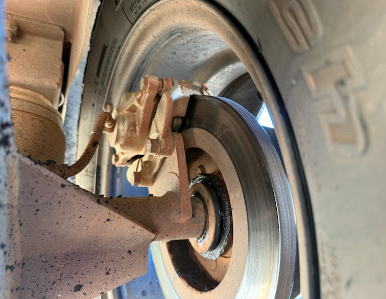 Close-up of a vehicle's brake system. A rusty caliper clamps onto a disc brake. — Centre Trailer Sales In Alice Springs, NT