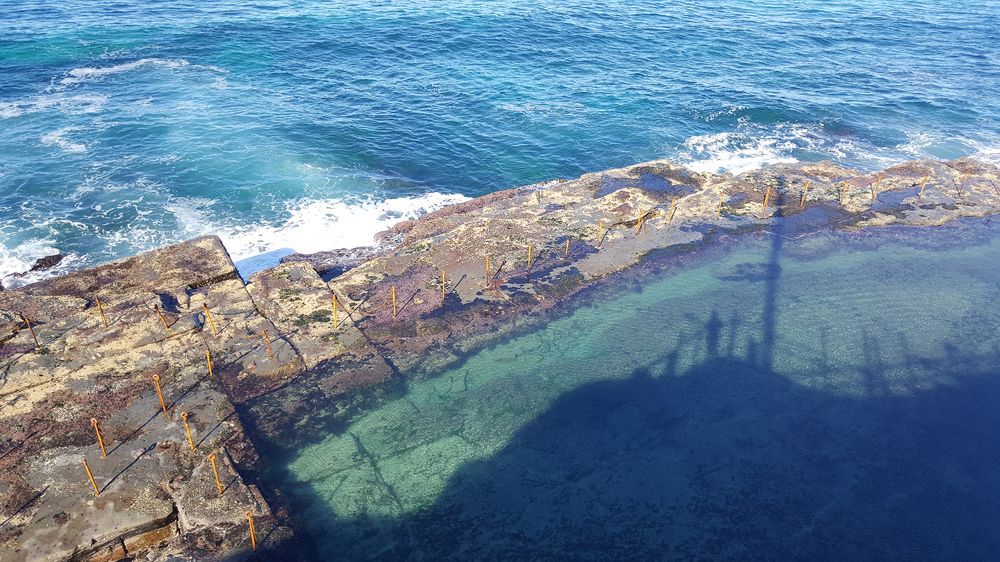 A Pool of Water Surrounded by Rocks Next to the Ocean — Coastal Kerb and Concrete In Morisset, NSW