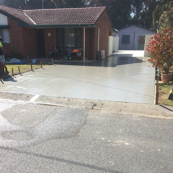 A Brick House With a Concrete Driveway in Front of It — Coastal Kerb and Concrete In Buff Point, NSW