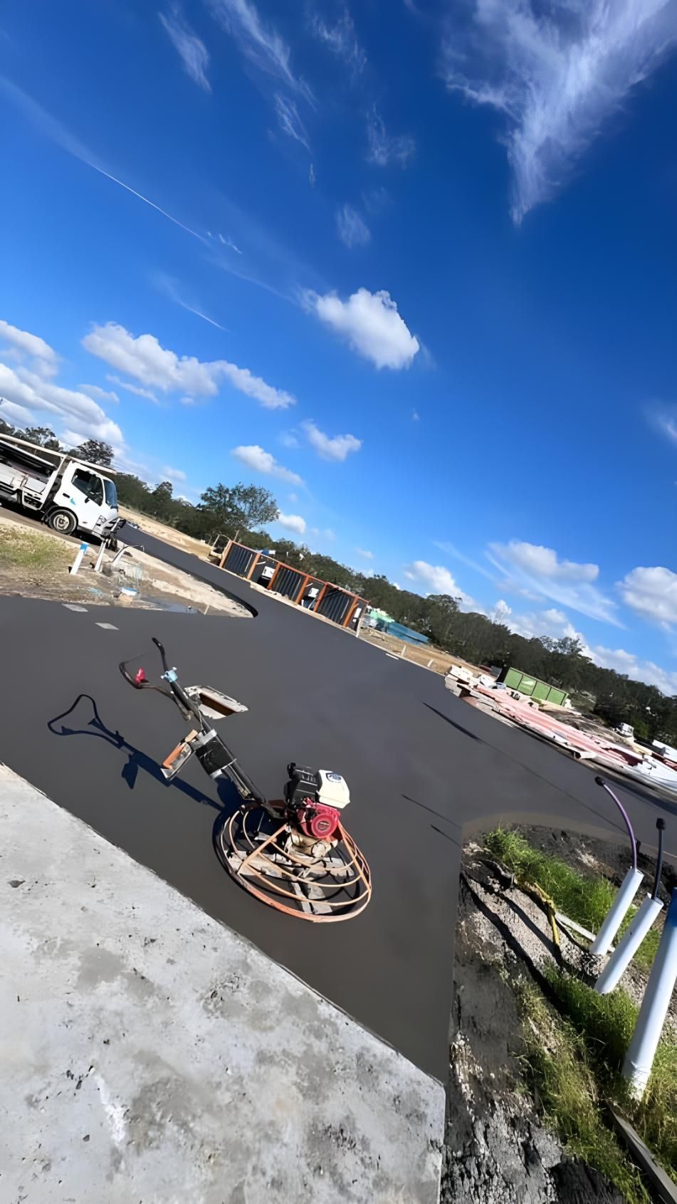 A Concrete Finisher is Sitting on the Side of a Road — Coastal Kerb and Concrete In Wyee, NSW