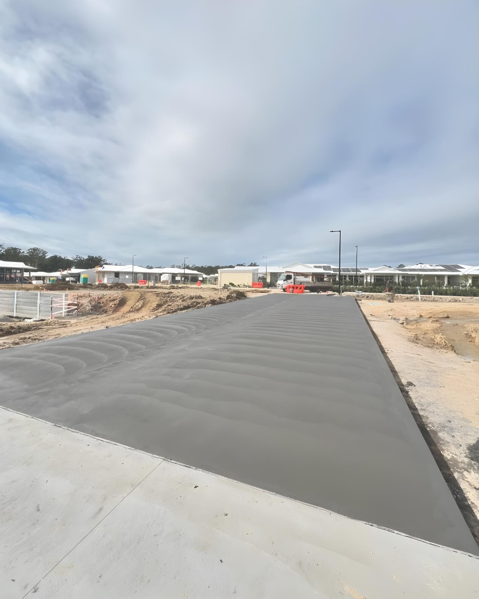A Concrete Road With a Lot of Buildings in the Background — Coastal Kerb and Concrete In Woongarrah, NSW