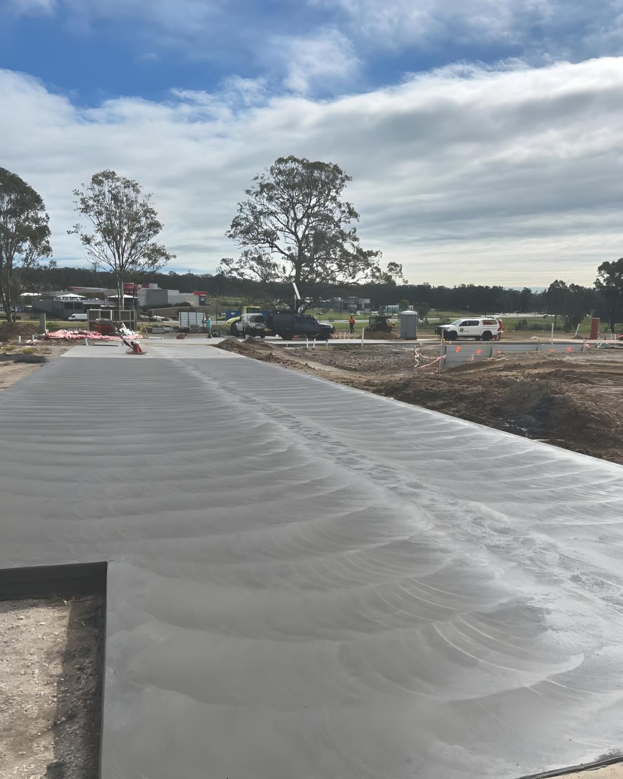 A Concrete Driveway is Being Built in a Field With Trees in the Background — Coastal Kerb and Concrete In Woongarrah, NSW