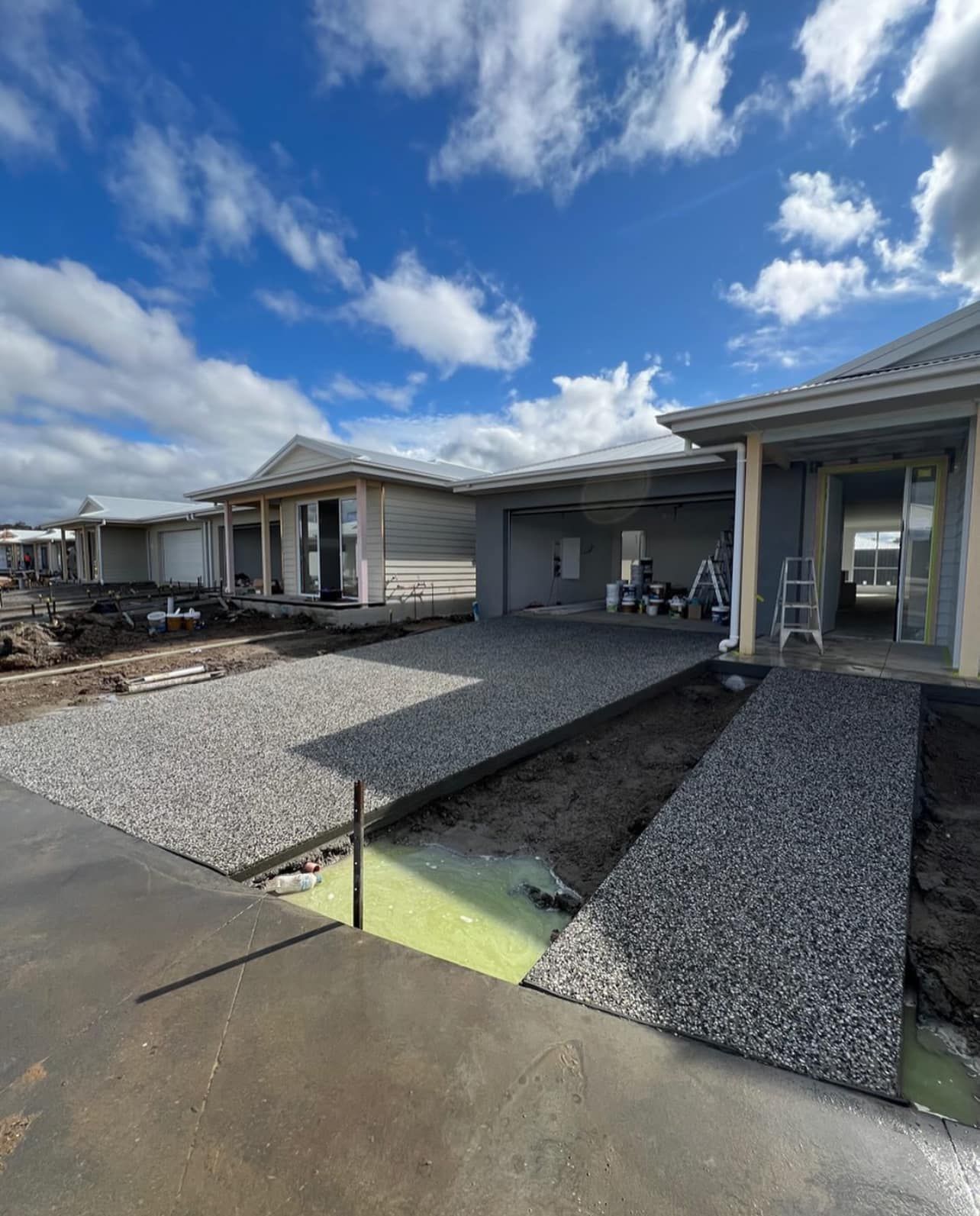 A House is Being Built on a Sunny Day With a Lot of Gravel in Front of It — Coastal Kerb and Concrete In Lake Macquarie, NSW