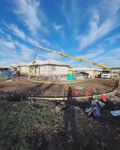 A Construction Site With a Crane and a House in the Background — Coastal Kerb and Concrete In Buff Point, NSW
