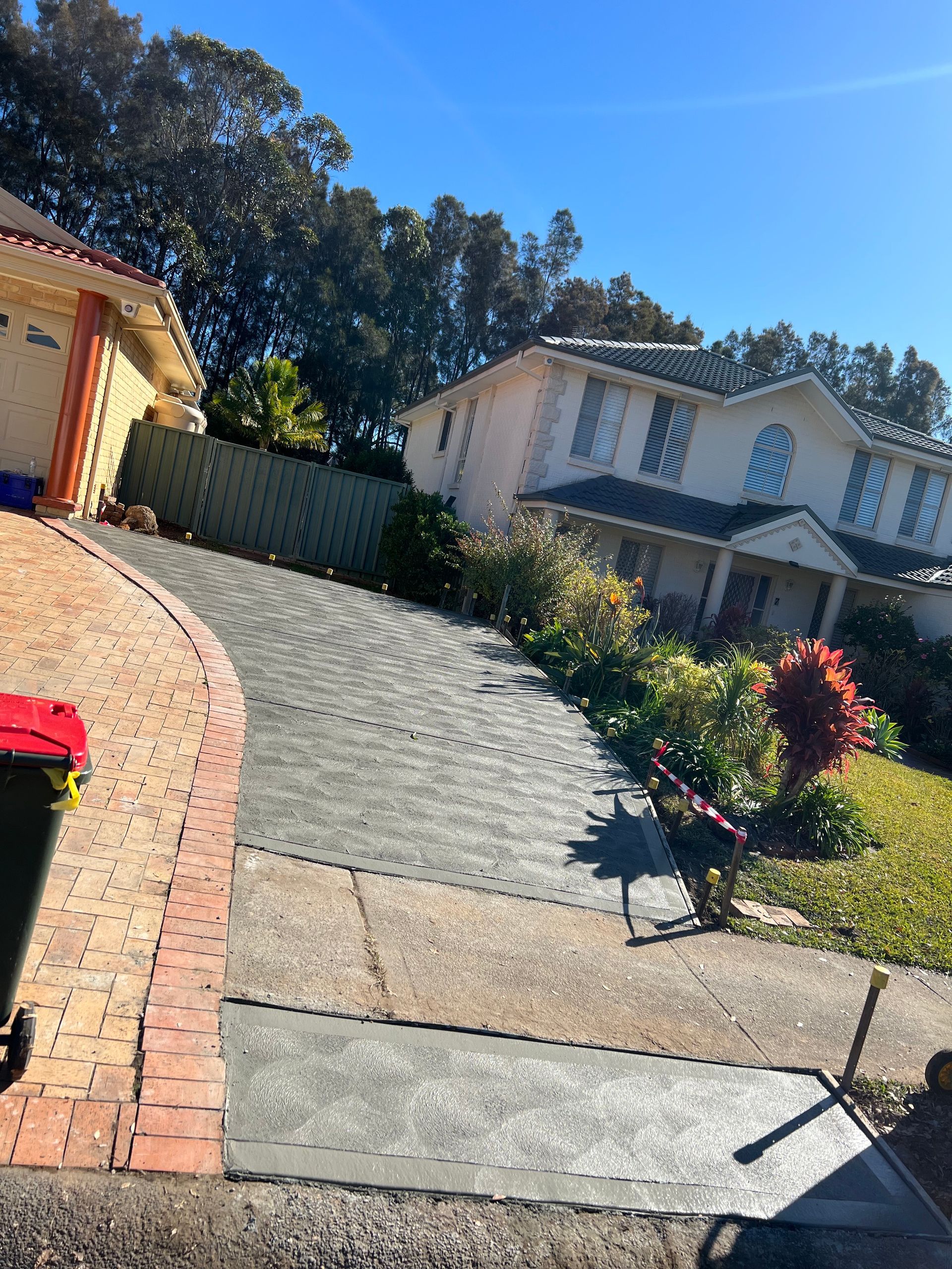 A House With a Brick Driveway and a Trash Can in Front of It — Coastal Kerb and Concrete In Buff Point, NSW