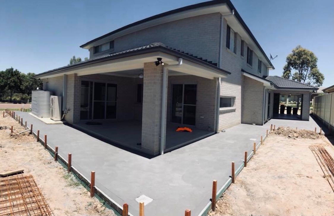 A Large House With a Concrete Patio in Front of It — Coastal Kerb and Concrete In Buff Point, NSW