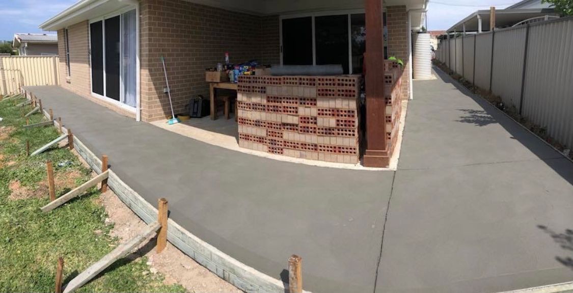 A Brick House With a Concrete Driveway in Front of It — Coastal Kerb and Concrete In Buff Point, NSW
