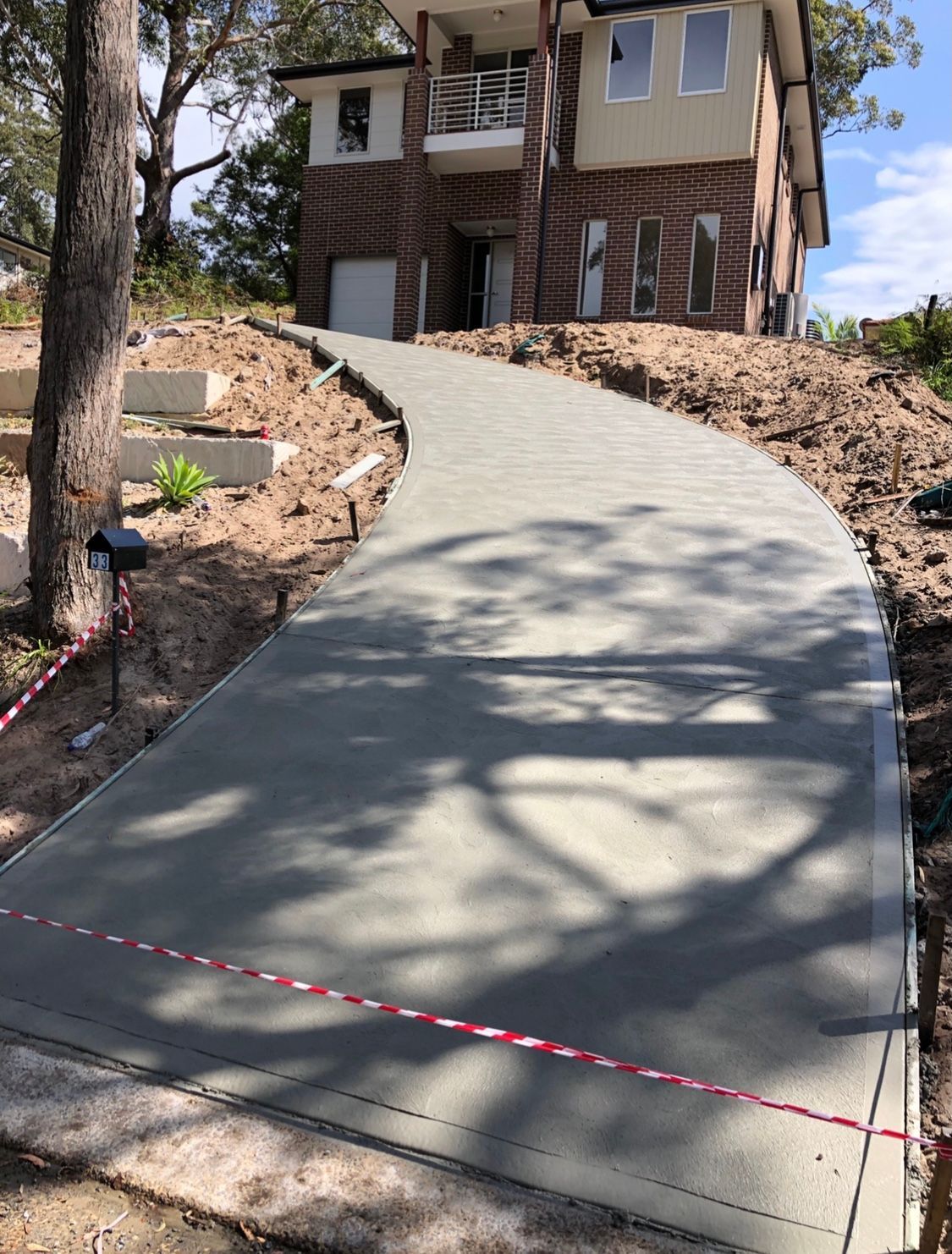 A Concrete Driveway is Being Built in Front of a House — Coastal Kerb and Concrete In Buff Point, NSW