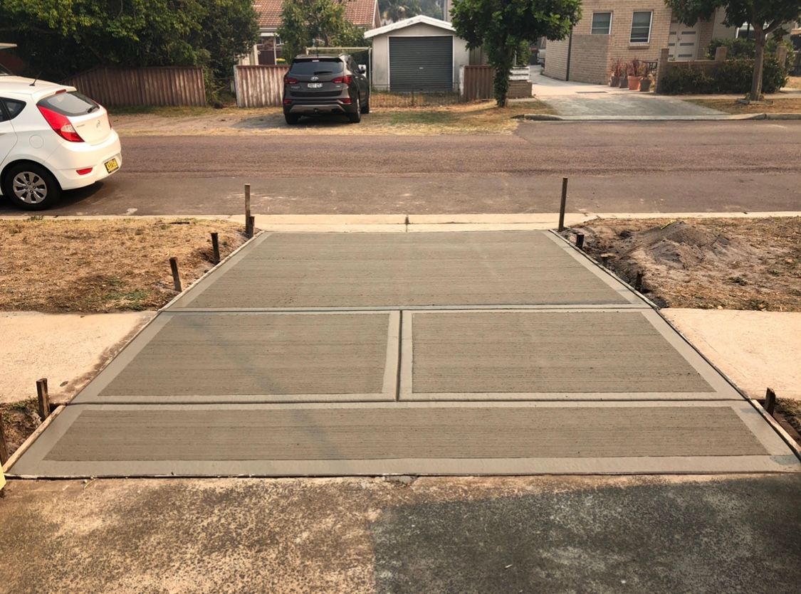 A White Car is Parked on the Side of the Road Next to a Concrete Driveway — Coastal Kerb and Concrete In Buff Point, NSW
