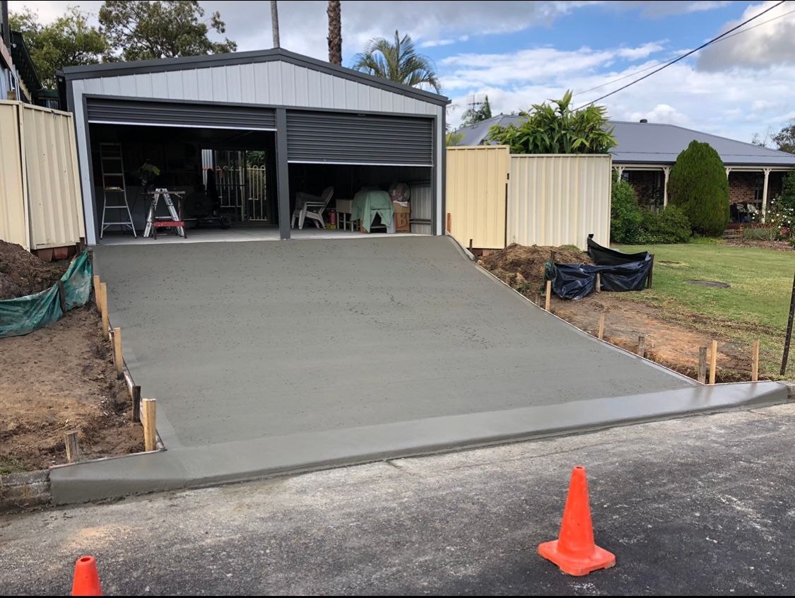 A Concrete Driveway is Being Built in Front of a Garage — Coastal Kerb and Concrete In Buff Point, NSW