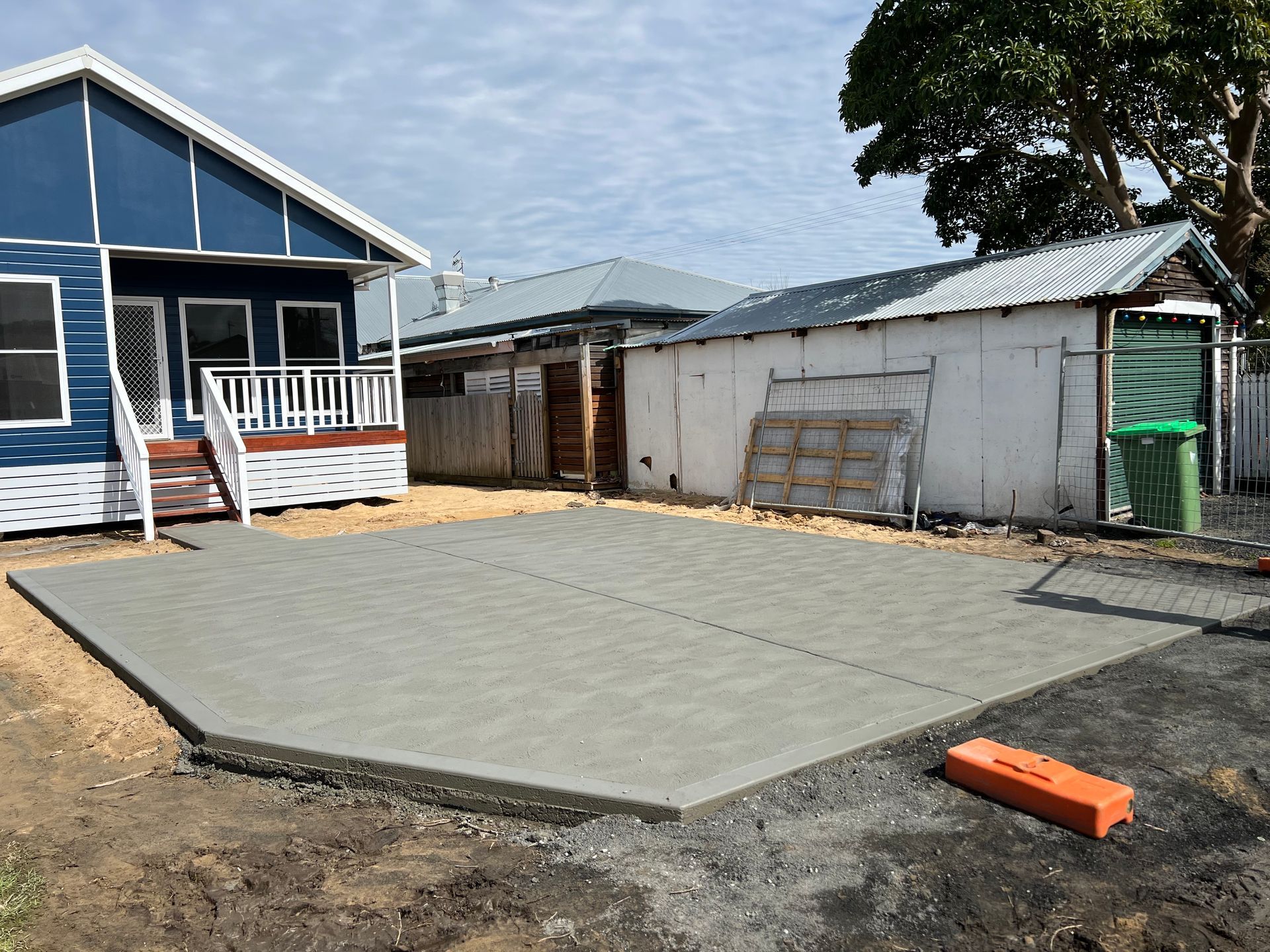 A Concrete Patio is Being Built in Front of a House — Coastal Kerb and Concrete In Erina, NSW