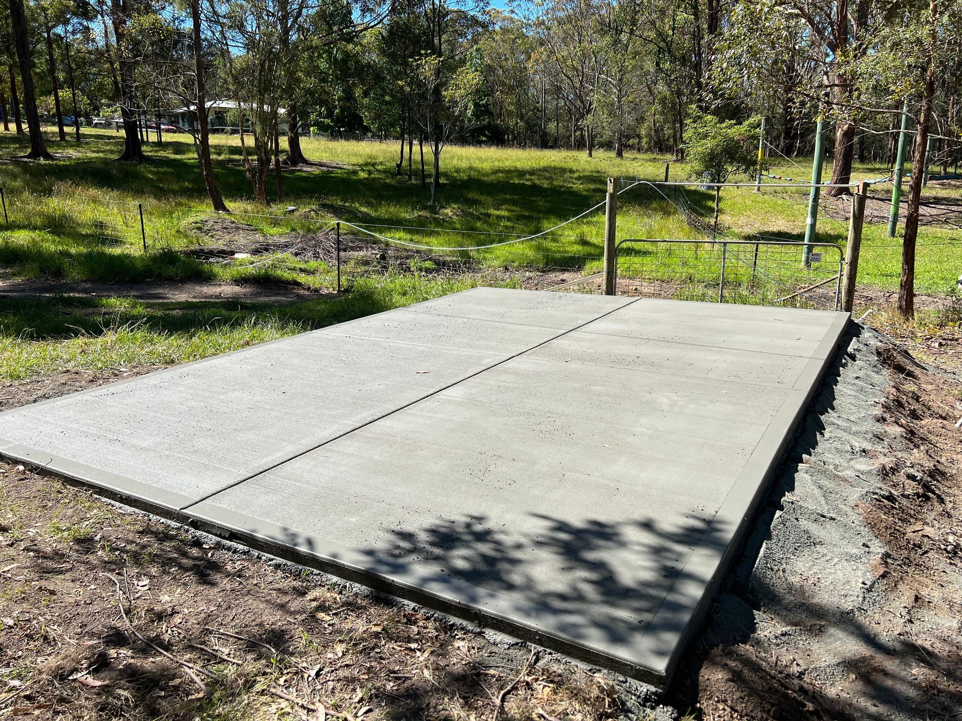 A Large Concrete Slab is Sitting in the Middle of a Grassy Field — Coastal Kerb and Concrete In Erina, NSW