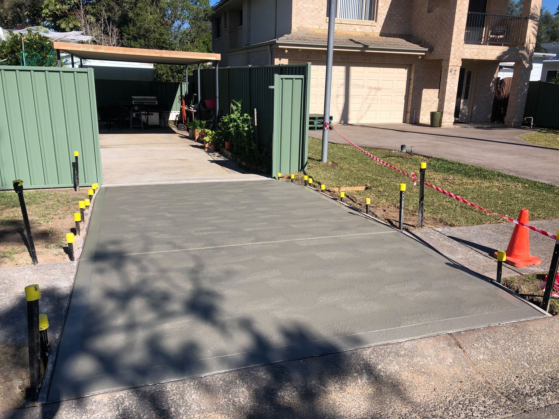 A Concrete Driveway is Being Built in Front of a House — Coastal Kerb and Concrete In Woy Woy, NSW