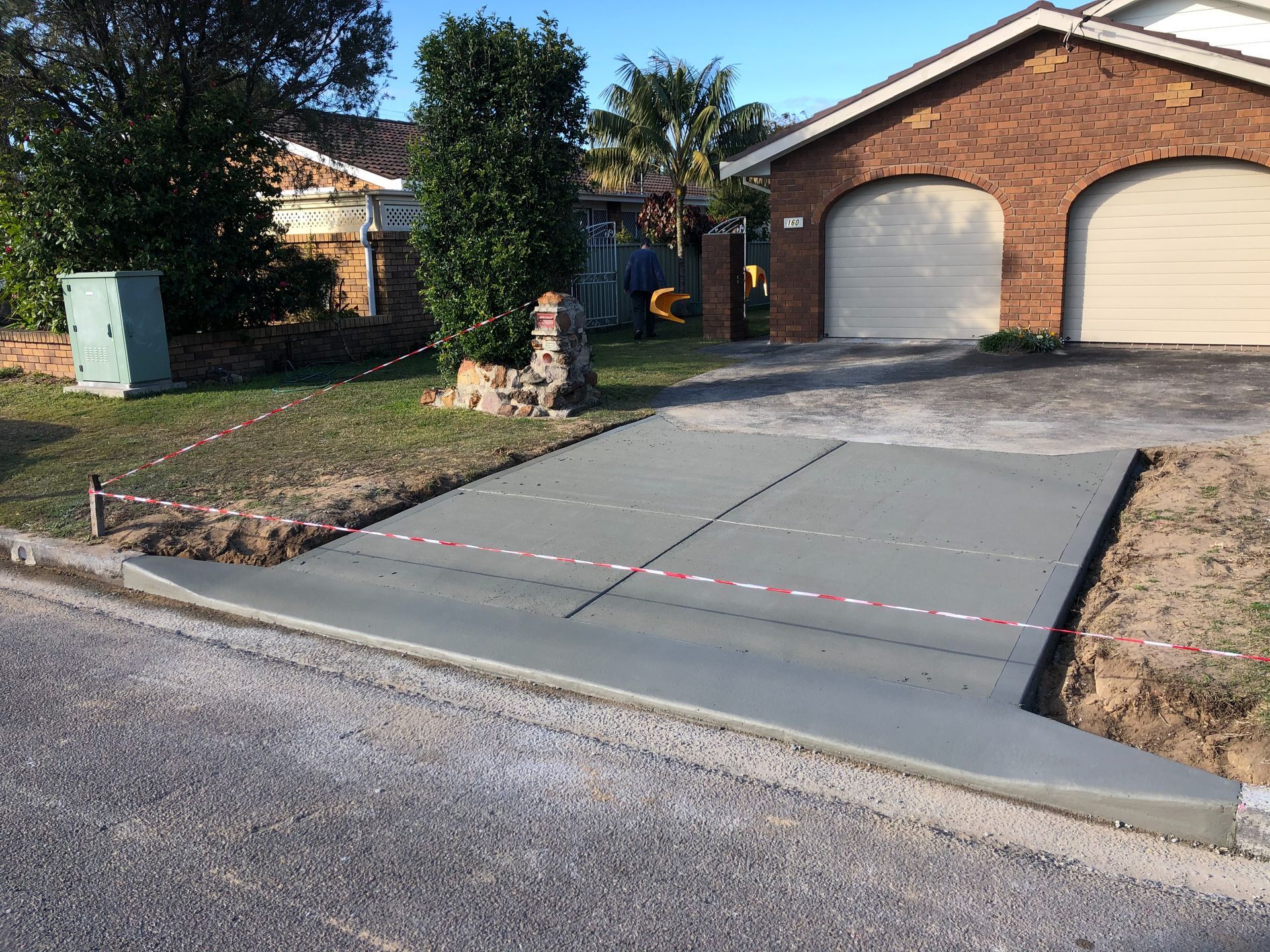 A Brick House With a Concrete Driveway in Front of It — Coastal Kerb and Concrete In Buff Point, NSW