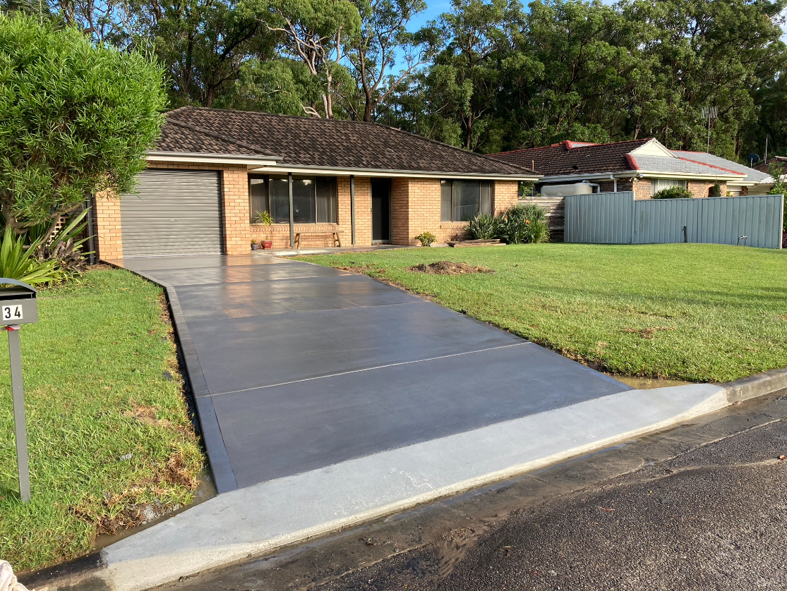 A Brick House With a Concrete Driveway in Front of It — Coastal Kerb and Concrete In Buff Point, NSW