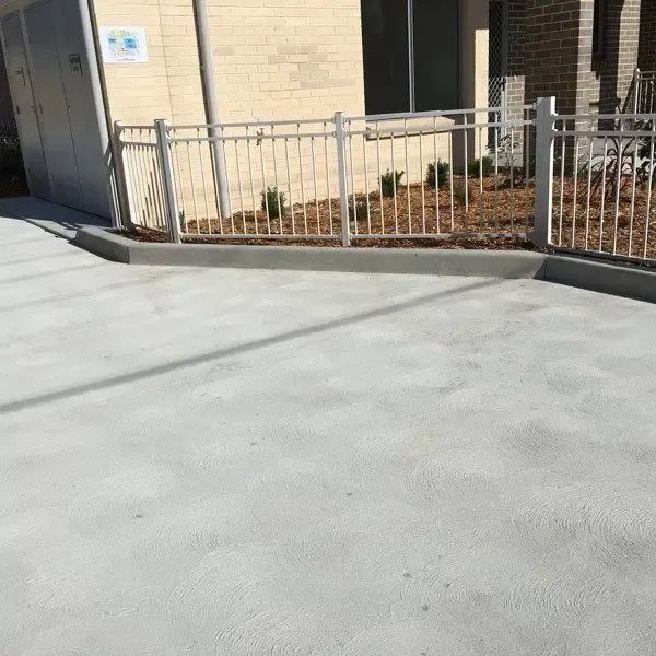 A Concrete Driveway With a Metal Fence in Front of a Building — Coastal Kerb and Concrete In Buff Point, NSW