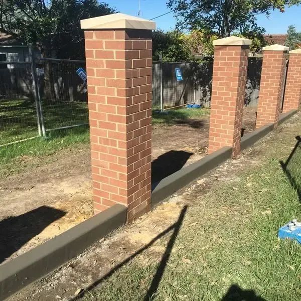 A Brick Fence is Being Built in a Yard — Coastal Kerb and Concrete In Buff Point, NSW