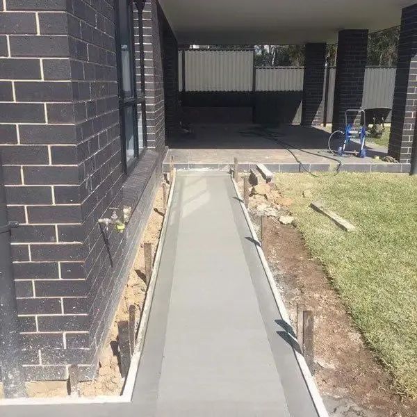 A Concrete Walkway is Being Built in Front of a Brick House — Coastal Kerb and Concrete In Buff Point, NSW