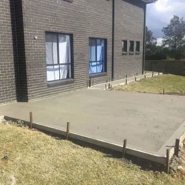 A Brick Building With a Concrete Patio in Front of It — Coastal Kerb and Concrete In Buff Point, NSW