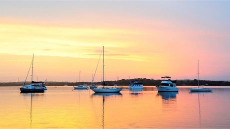 A Group of Boats Are Docked in the Water at Sunset — Coastal Kerb and Concrete In Wyee, NSW