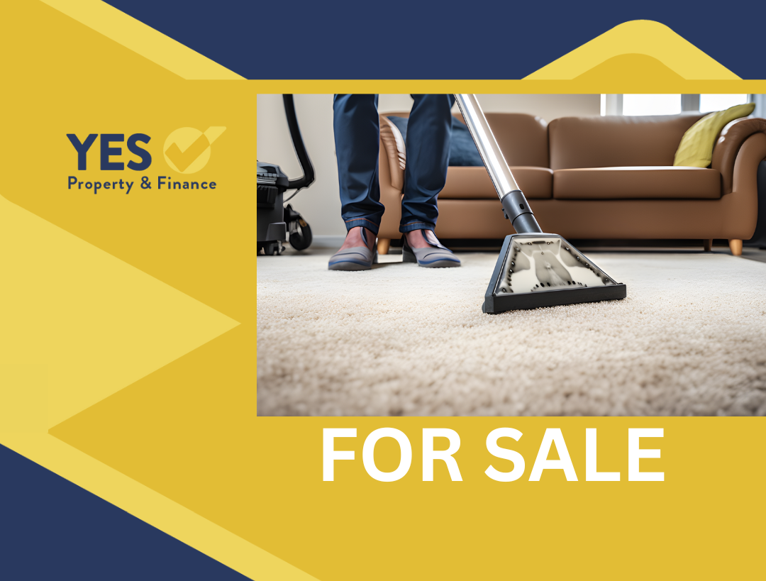 A person vacuuming a light-colored rug in a living room;