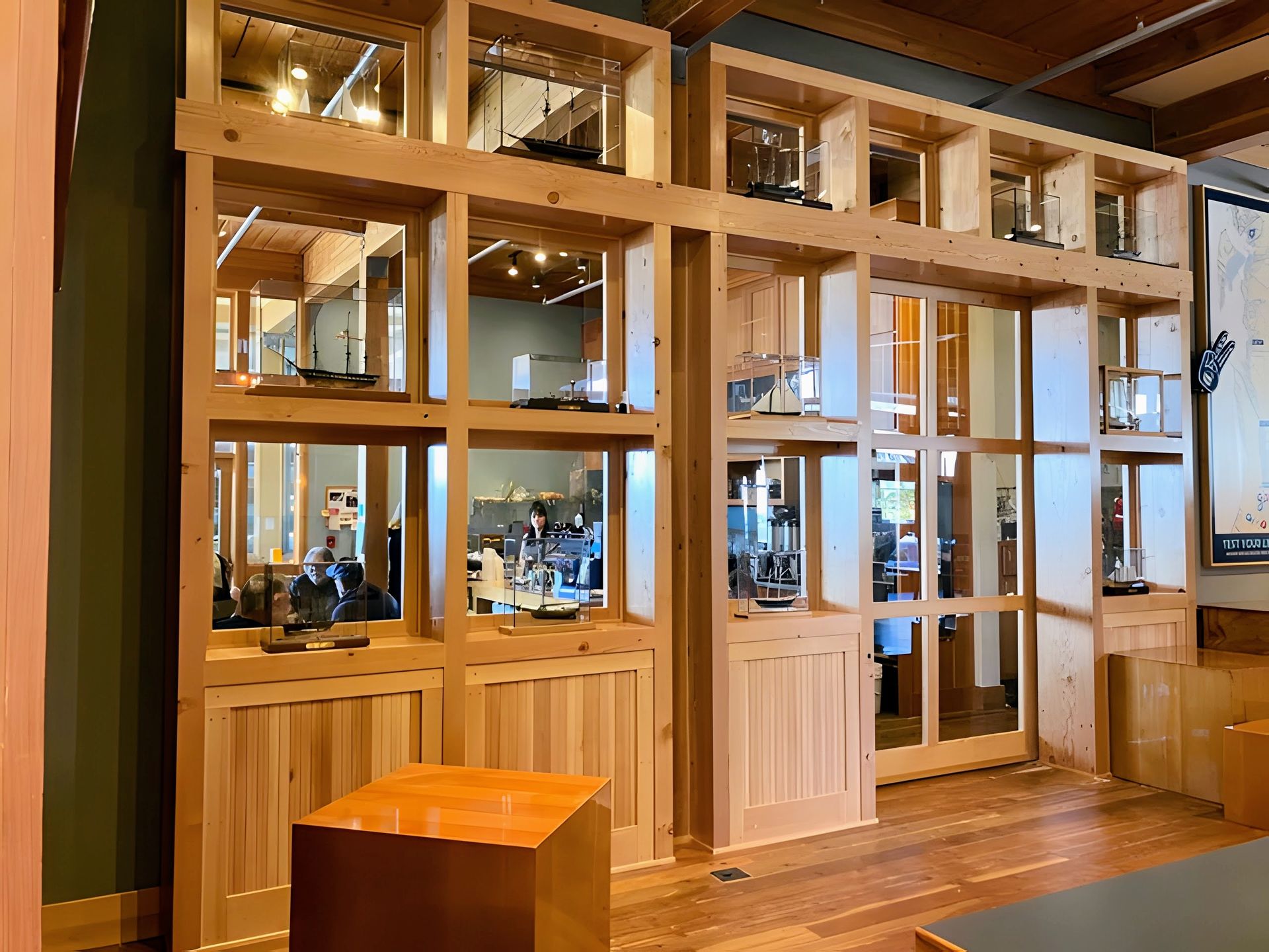 Wood-framed glass entrance with a wooden door, warm interior lighting, and a small wooden stool in front