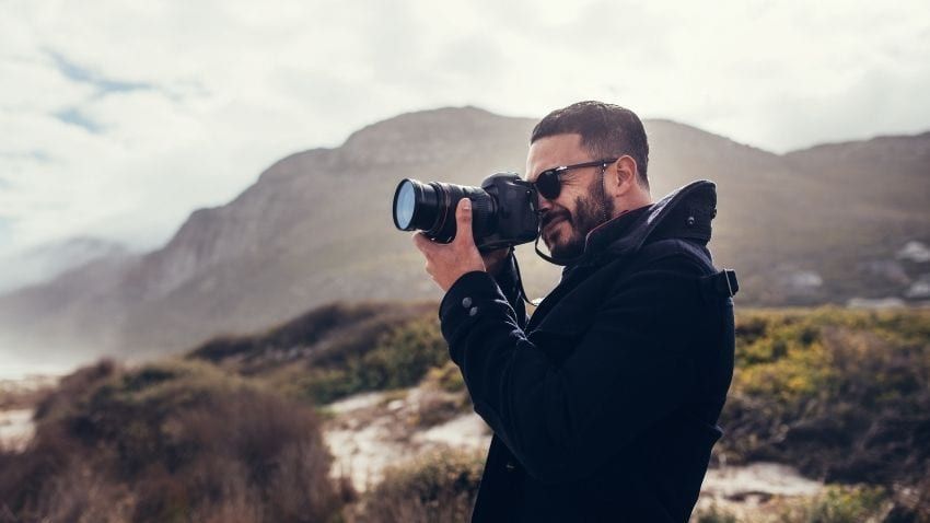 Um homem está tirando uma foto de uma montanha com uma câmera.