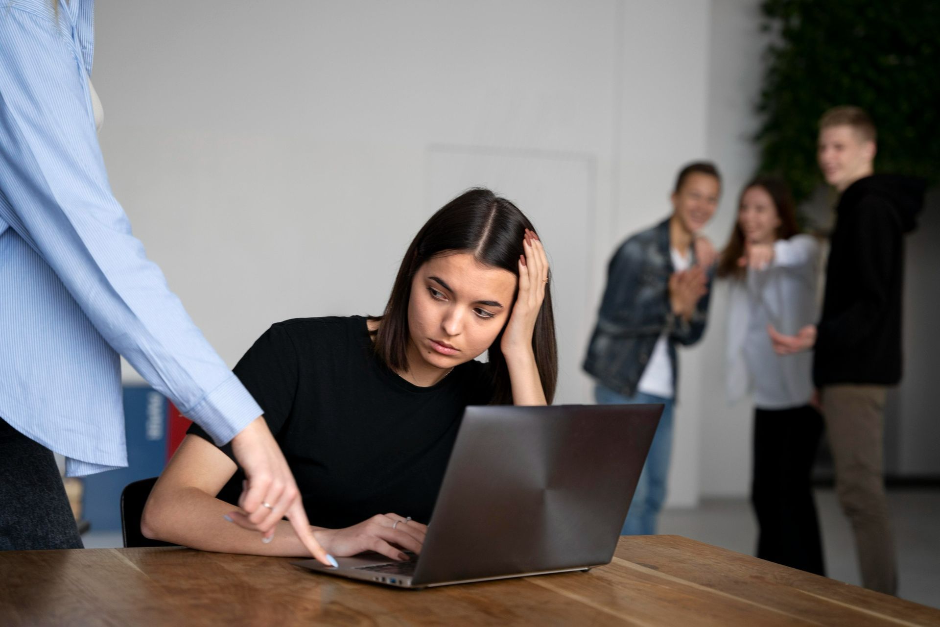 Uma mulher está sentada à mesa usando um laptop.