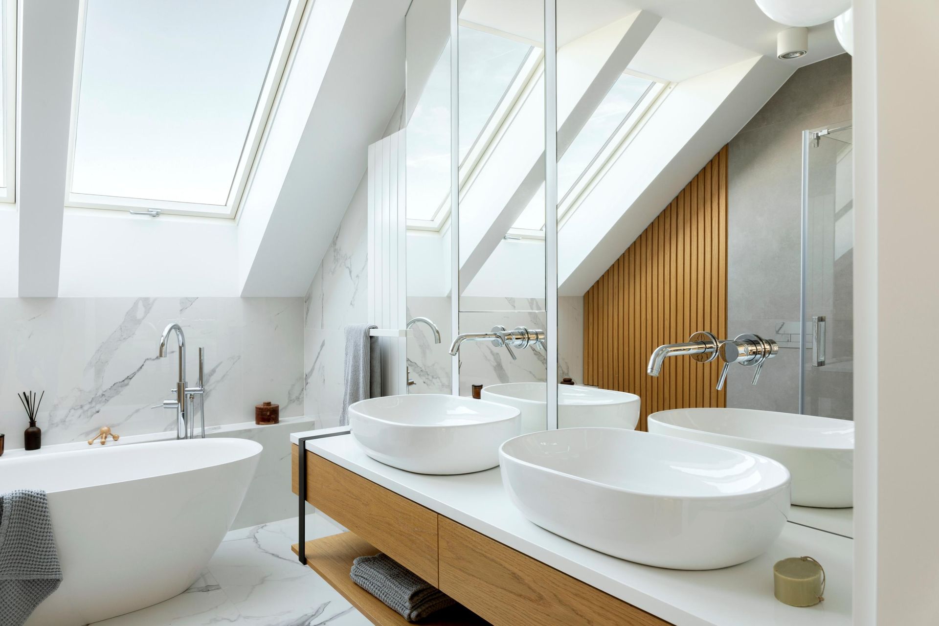 Bright modern bathroom with skylights, freestanding tub, double sinks, and large mirror