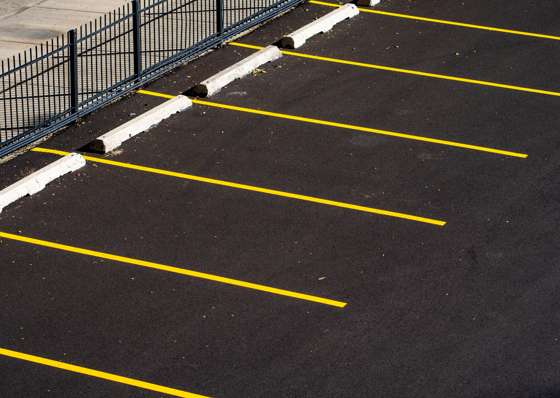 Empty parking lot with yellow lines and wheel stops.